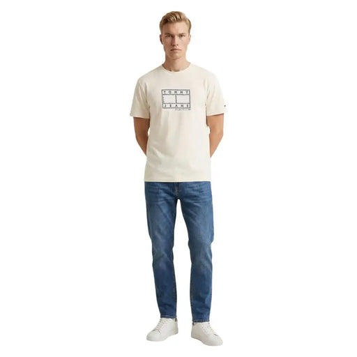 Cremefarbenes Tommy Hilfiger Jeans Herren-T-Shirt aus Bio-Baumwolle mit schwarzem Logo und Tennisplatzmotiv auf der Vorderseite