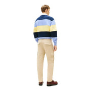 Ein Mann, der einen marineblauen, hellblauen und gelb gestreiften Rugbypullover trug, kombiniert mit Tommy Hilfiger Jeanshose