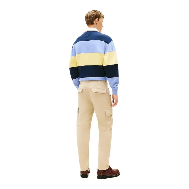 Ein Mann, der einen marineblauen, hellblauen und gelb gestreiften Rugbypullover trug, kombiniert mit Tommy Hilfiger Jeanshose