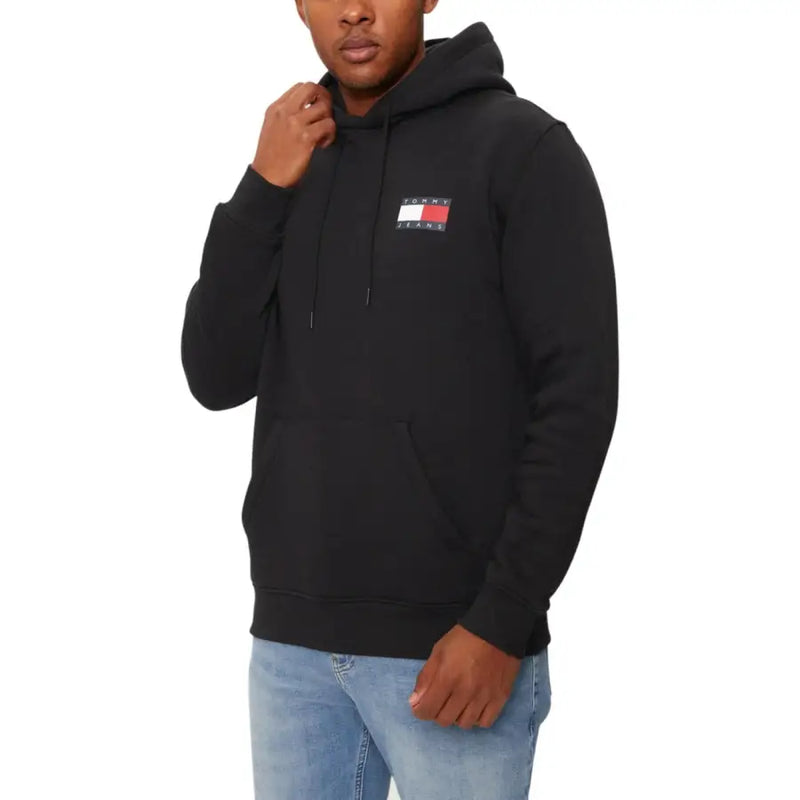 Black hooded sweatshirt with logo patch worn with light wash jeans by a male model