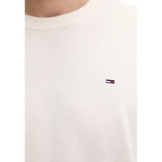 Cremefarbener Strickpullover mit Rundhalsausschnitt aus Bio-Baumwolle mit gesticktem Tommy Hilfiger Logo auf der linken Brust.