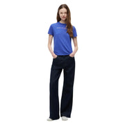 Eine Frau trägt ein leuchtendes Königsblau Tommy Hilfiger Bio-Baumwoll-T-Shirt kombiniert mit dunkelblauen, weit geschnittenen Jeans.
