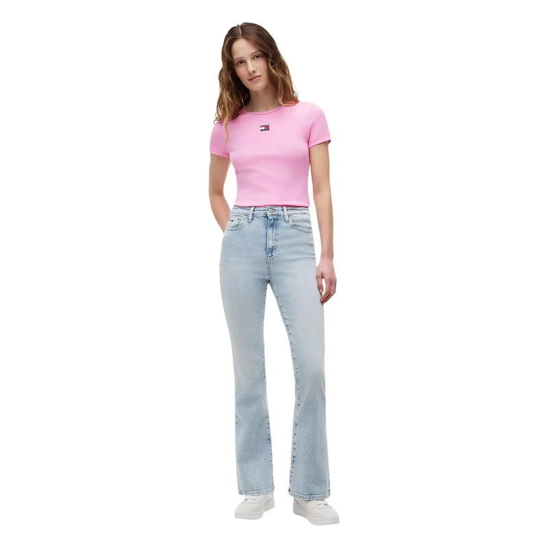 Eine Frau trägt ein pinkfarbenes, geripptes Baumwoll-Crop-Shirt von Tommy Hilfiger, kombiniert mit einer hellen Schlagjeans.