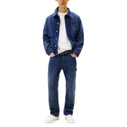 Tommy Hilfiger Herrenjeans aus blauer Bio-Baumwolle, kombiniert mit einer dunkelblauen Jeansjacke mit Knopfleiste und Brusttasche.