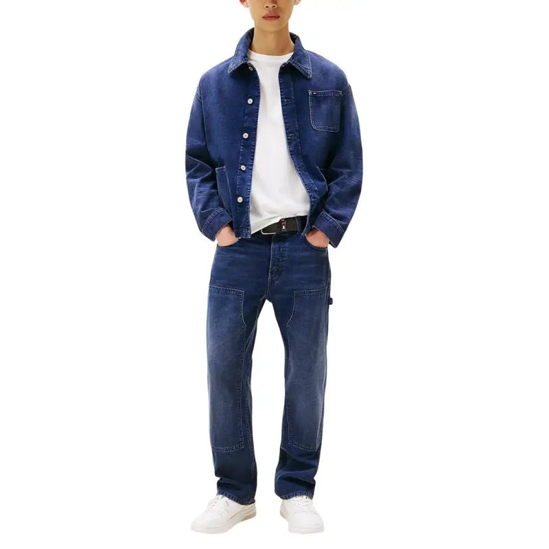 Tommy Hilfiger Herrenjeans aus blauer Bio-Baumwolle, kombiniert mit einer dunkelblauen Jeansjacke mit Knopfleiste und Brusttasche.