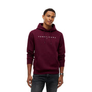 Kastanienbrauner Herren-Kapuzenpullover von Tommy Hilfiger mit weißem Logo und Vordertasche, gepaart mit einem grünen T-Shirt aus Bio-Baumwolle in normaler Passform