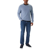 Hellblauer Tommy Hilfiger Rundhalspullover mit schwarzem Rippstrickkragen, kombiniert mit einer blauen Slim-Fit-Jeans aus Bio-Baumwolle.