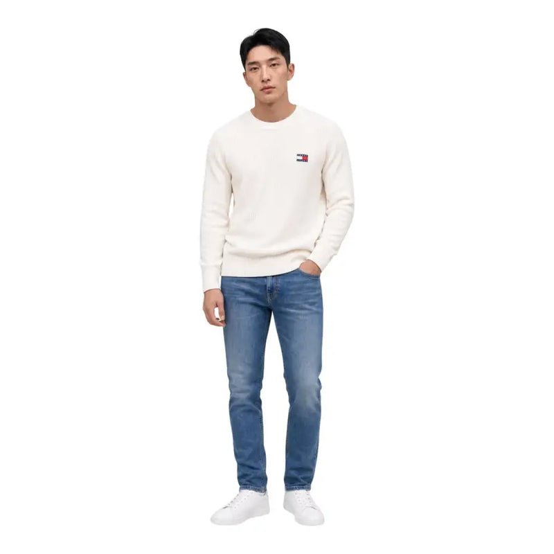 Ein cremefarbener Tommy Hilfiger Pullover aus Bio-Baumwolle mit Rundhalsausschnitt und kleinem, gesticktem Logo auf der linken Brust.
