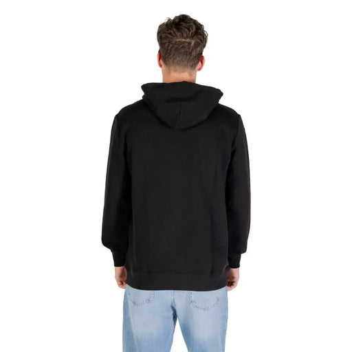 Men’s black organic cotton hooded sweatshirt with light wash blue jeans displayed for Tommy Hilfiger