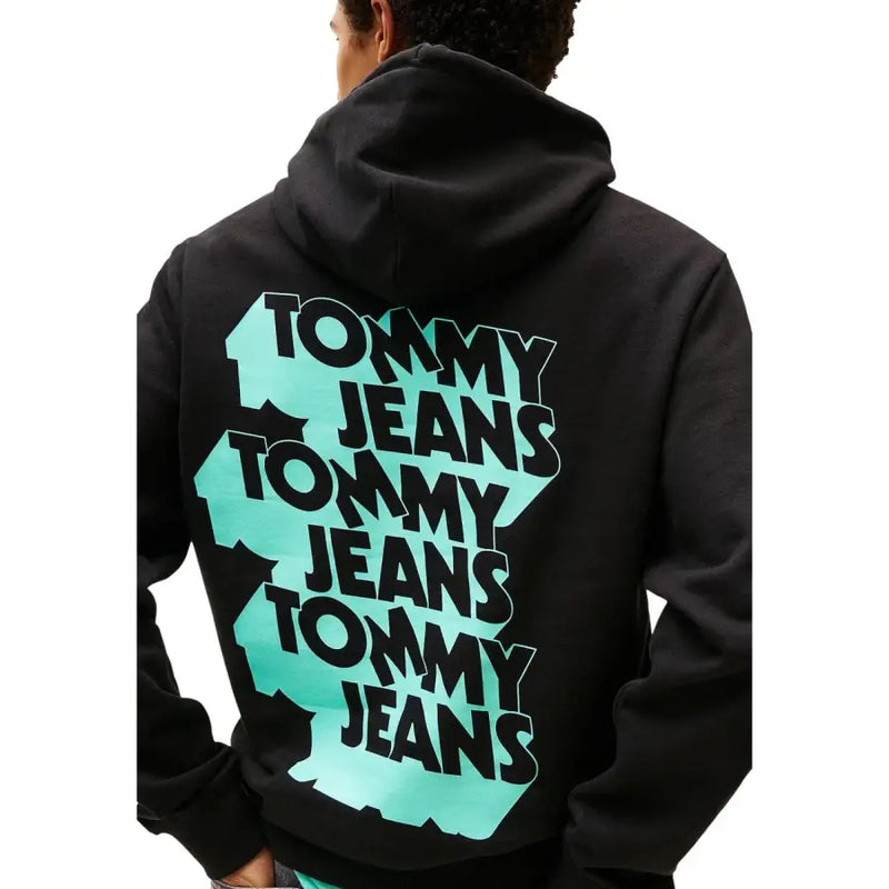 Rückansicht eines schwarzen Tommy Hilfiger Herren-Sweatshirts mit Kapuze aus Bio-Baumwolle und auffälligem, gestapeltem Tommy Jeans-Logo in Schwarz und Türkis.