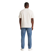 Ein Mann, der einen cremefarbenen Tommy Hilfiger Weißes, kurzärmeliges Bio-Baumwoll-T-Shirt für Herren mit blauer Jeans