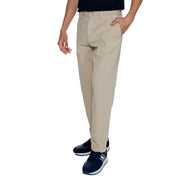 Men’s beige chino pants paired with a dark blue top and athletic shoes in a Tommy Hilfiger ensemble