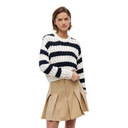 Eine Frau, die einen marineblau-weiß gestreiften Rippstrickpullover aus blauer Bio-Baumwolle trägt. Tommy Hilfiger