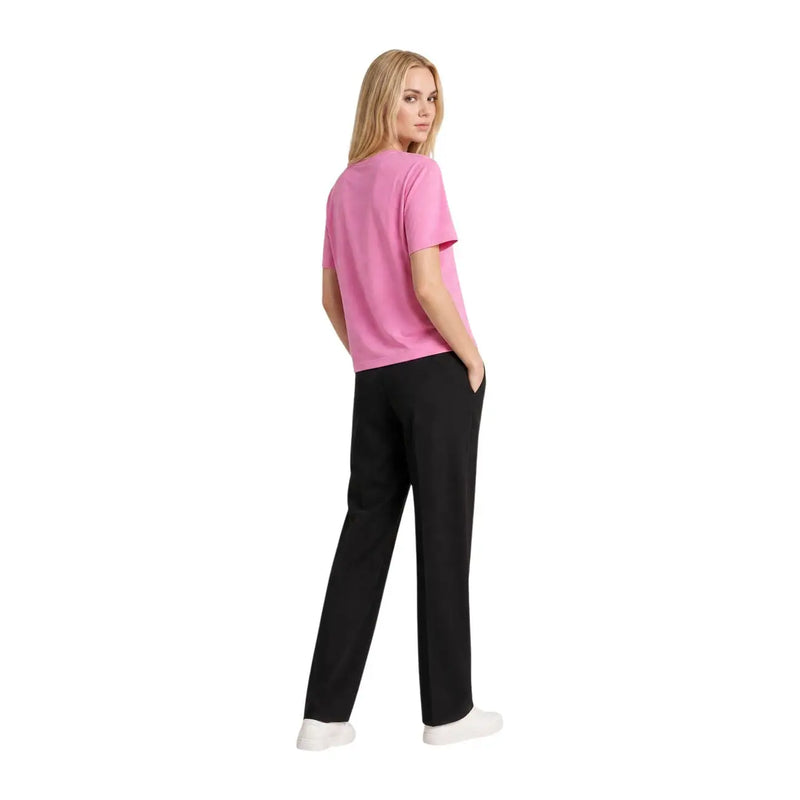 Eine Frau trägt ein leuchtendes Fuchsia Tommy Hilfiger Kurzarm-T-Shirt aus Bio-Baumwolle mit schwarzer Hose