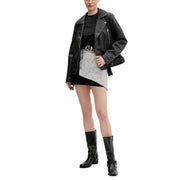 Schwarze Bikerjacke aus Leder mit silbernen Reißverschlüssen und Druckknöpfen, kombiniert mit einem schwarzen Kurzarm-T-Shirt aus Bio-Baumwolle von Tommy Hilfiger für Damen.