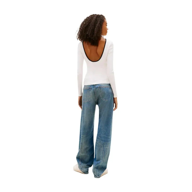 Back view of tommy hilfiger women white long sleeve organic cotton t-shirt with black trim paired with blue jeans