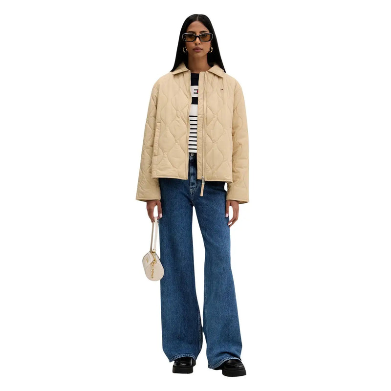 Beige Steppjacke mit klassischem Kragen und Frontreißverschluss, kombiniert mit hellblauen Tommy Hilfiger Damen-Jeans mit weitem Bein aus Baumwolle.