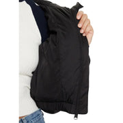 Woman wearing Tommy Hilfiger black nylon jacket with hood and turtleneck, white top, and blue jeans