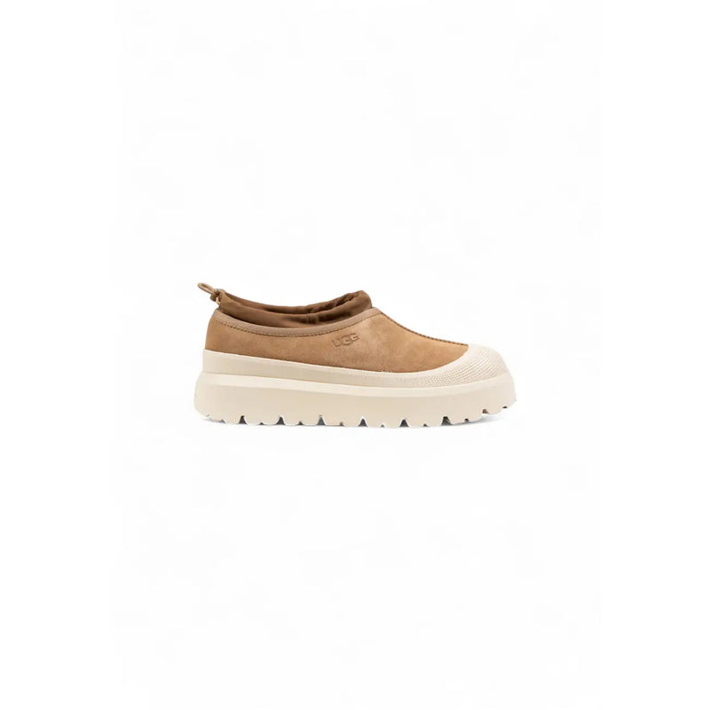 Beige Ugg Wildleder-Slipper für Herren mit cremefarbener, klobiger Sohle und Ugg-Logo – ideal für den Winter.