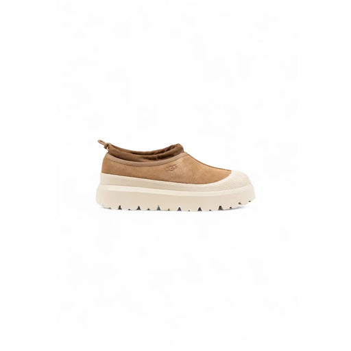 Beige Ugg Wildleder-Slipper für Herren mit cremefarbener, klobiger Sohle und Ugg-Logo – ideal für den Winter.
