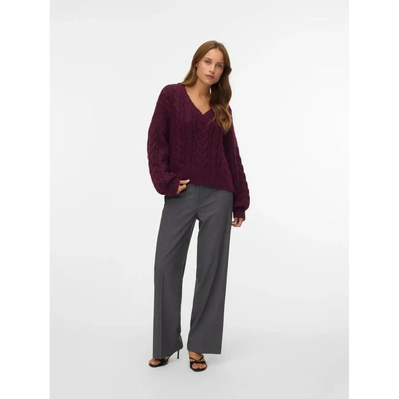 Ein tief burgunderroter Zopfstrickpullover mit V-Ausschnitt und langen Ärmeln, kombiniert mit vero moda graue Damenhose mit Reißverschluss und Knopf, normale Passform
