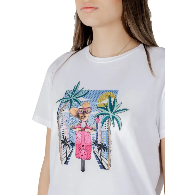 White cotton t-shirt featuring a vibrant cartoon graphic of a dog riding a pink scooter through a tropical cityscape
