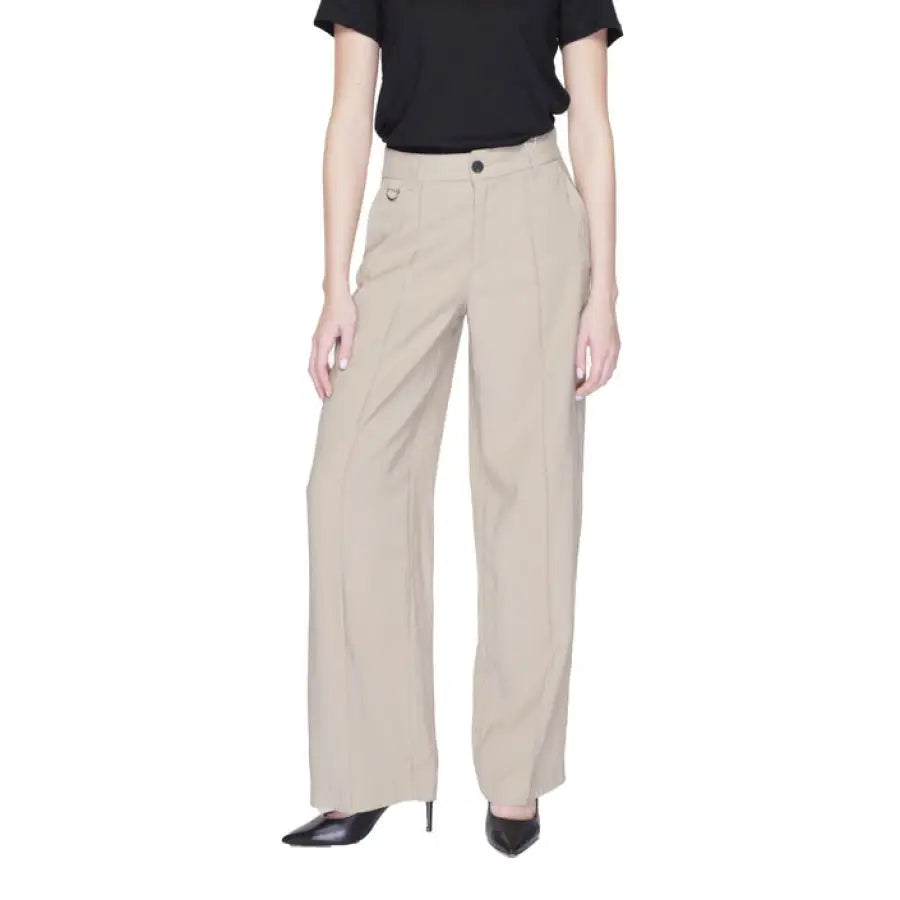 Woman in urban style clothing, black top and beige Only trousers