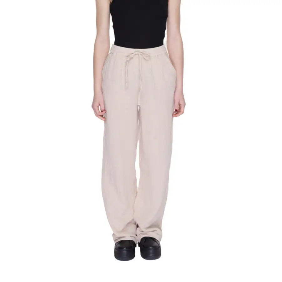 Woman in urban style clothing, black top and beige Only trousers