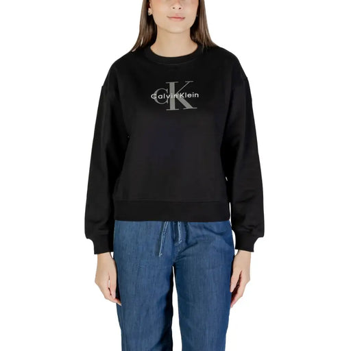 Frau, die ein schwarzes Calvin Klein Langärmeliges Sweatshirt und blaue Jeans mit Kordelzug