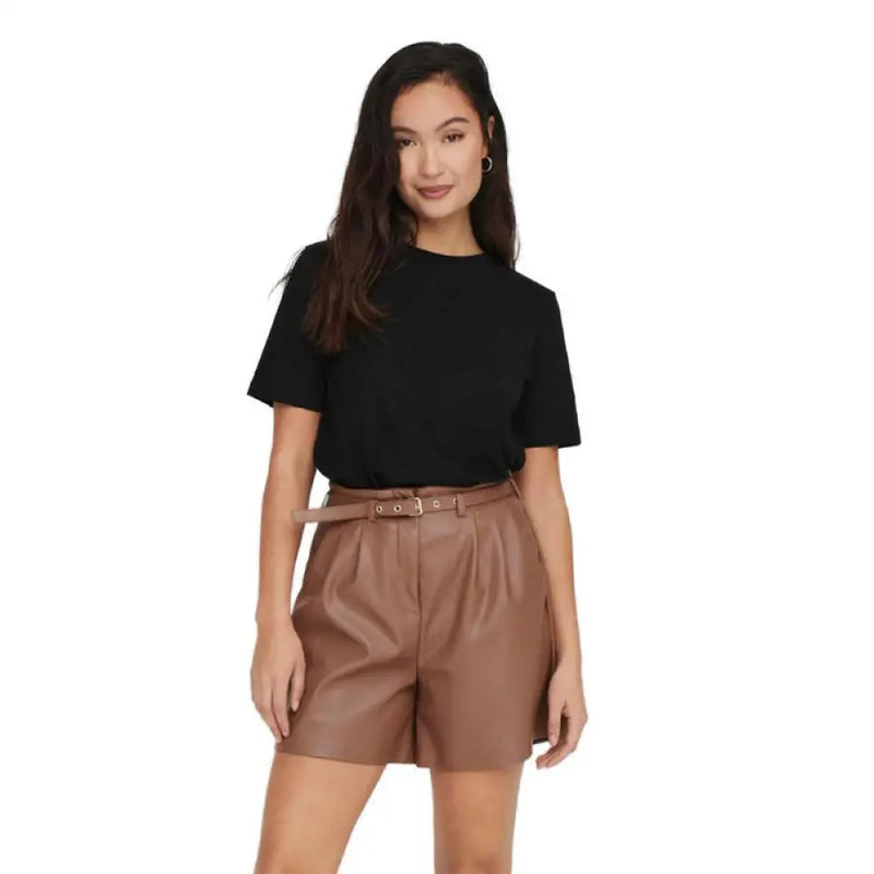 Woman wearing black t-shirt and brown faux leather shorts showcasing stylish casual look
