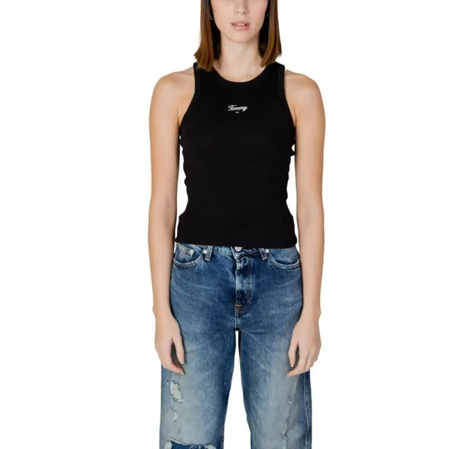 Woman in Tommy Hilfiger jeans and black tank top showcasing the brand’s style