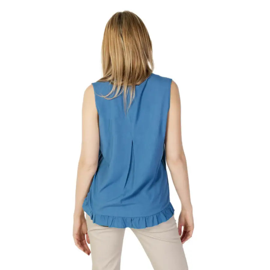 Woman modeling Sandro Ferrone blue top and beige pants in Sandro Ferrone undershirt ad