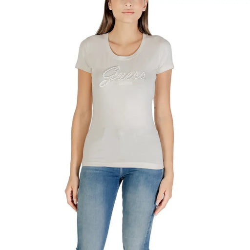 Frau trägt helle, eng anliegende Kleidung Guess T-shirt mit Strassmuster und blauen Jeans