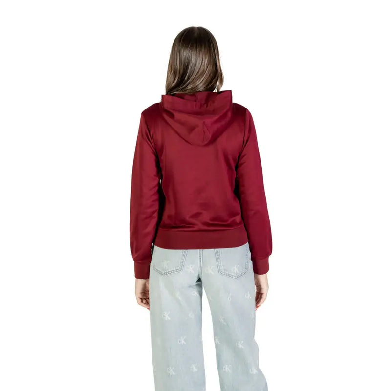 Woman wearing a maroon hoodie and light-wash wide-leg jeans in Calvin Klein Bordeaux sweatshirt