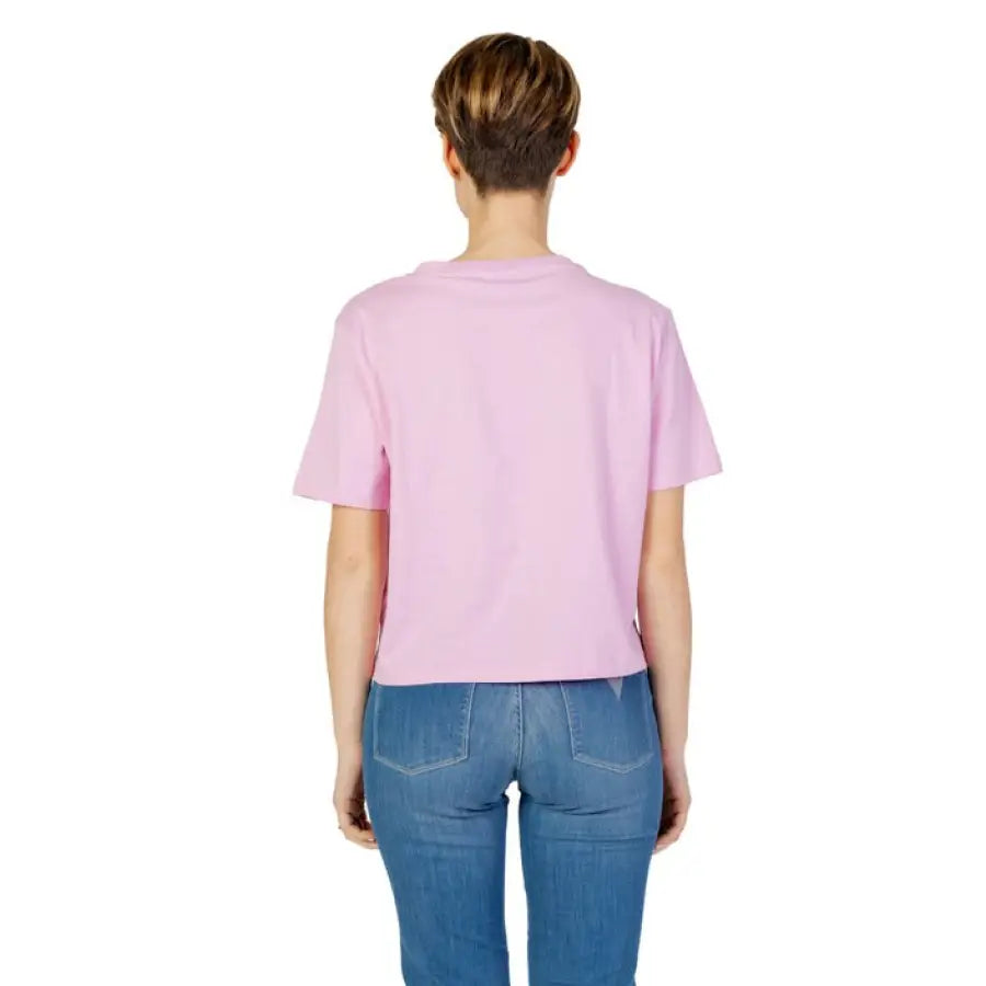 Guess Active woman in pink t-shirt, jeans showcasing urban style clothing