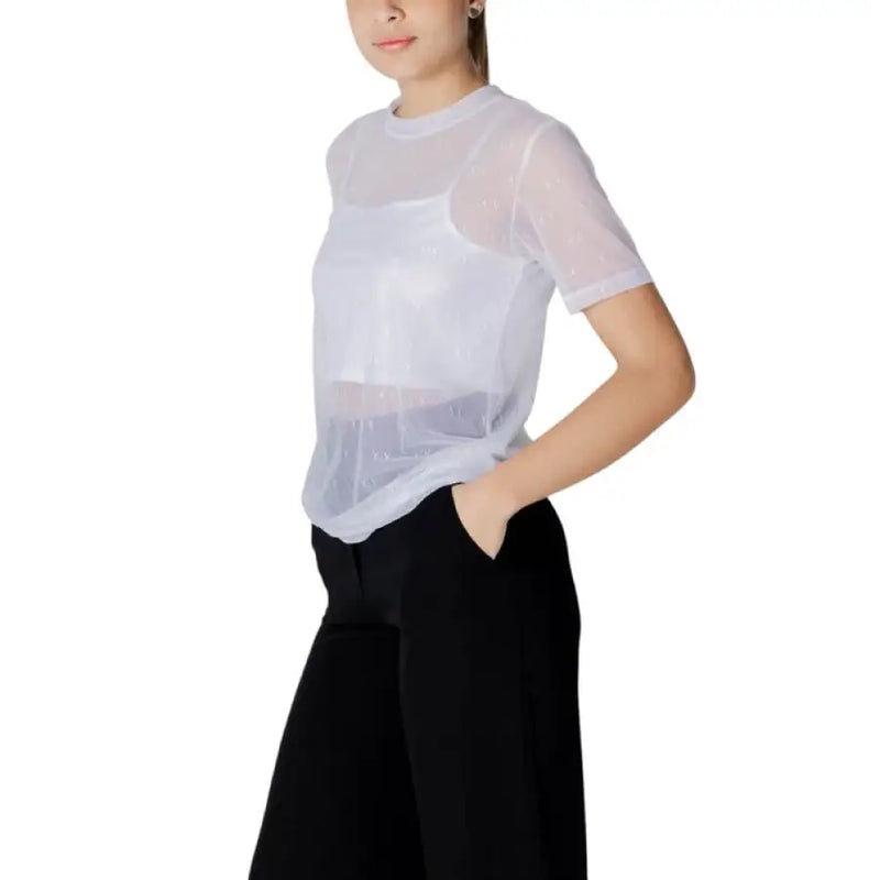 Woman wearing a sheer white top with black pants showcasing the Women’s Sheer Top with White Tank