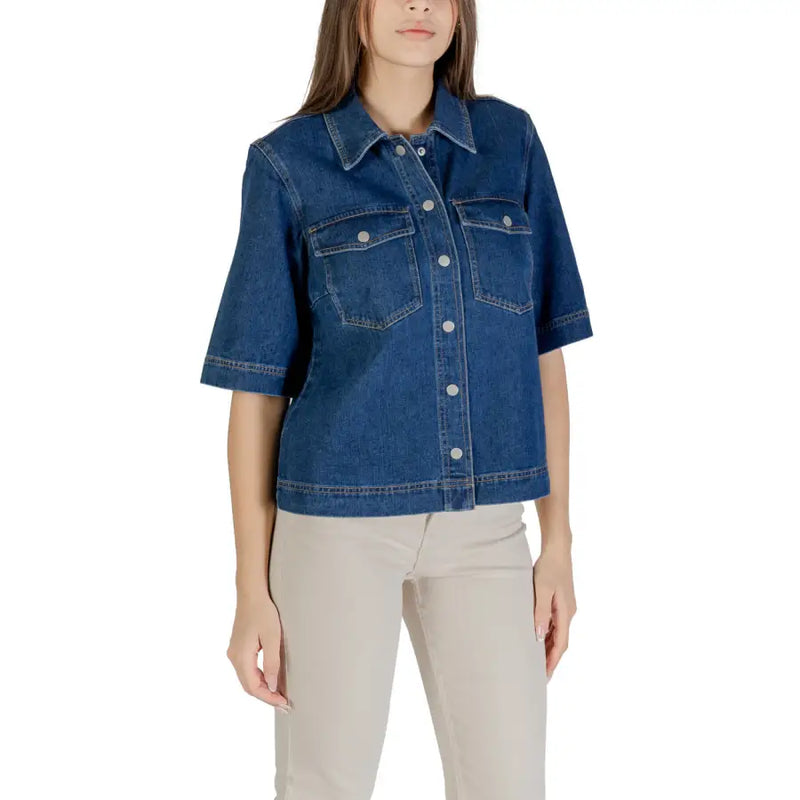 Frau trägt ein klassisches blaues Kurzarm-Baumwollhemd und eine helle Hose