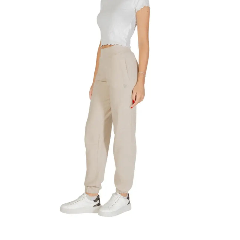 Woman wearing Guess beige cotton trousers with front pockets and white sneakers