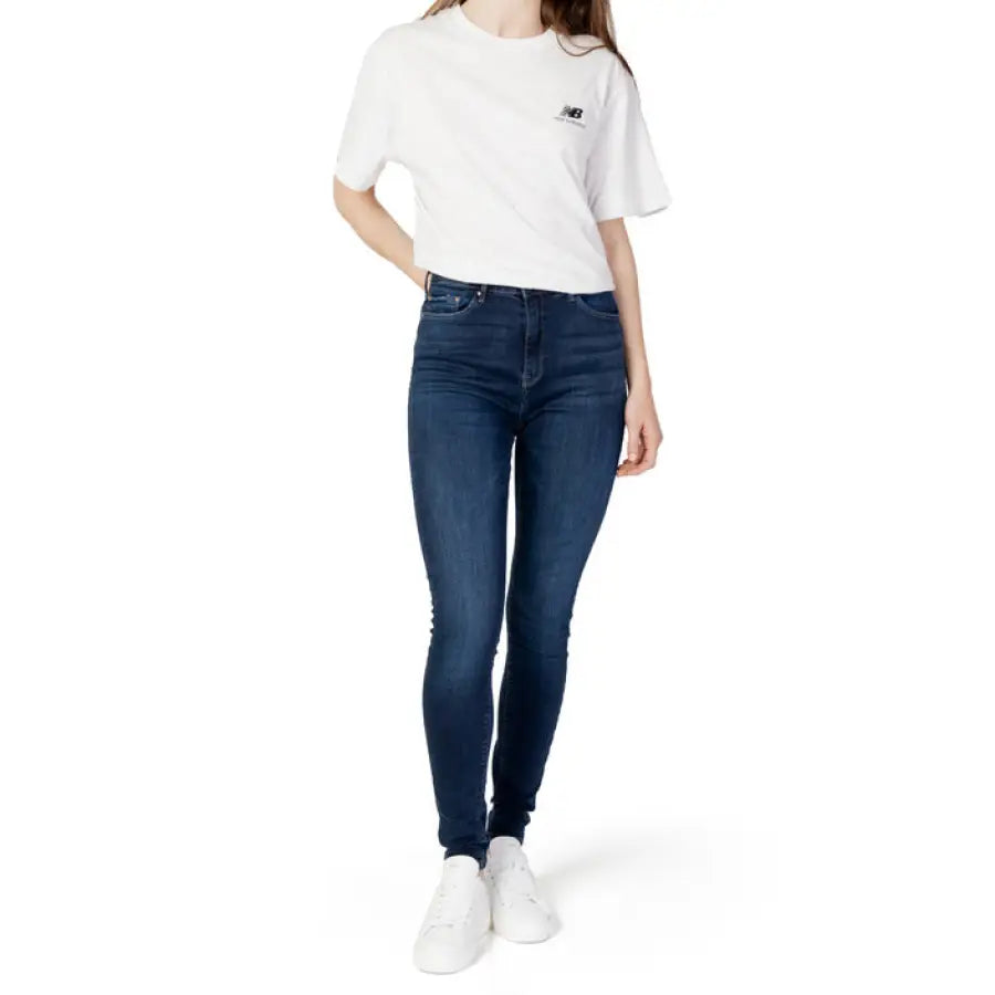 Woman in white t-shirt and Only women jeans against white backdrop, embodying urban city fashion