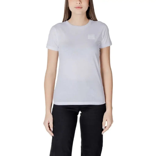 Frau trägt schwarzes Rundhals-T-Shirt mit weißem T-Shirt und schwarzer Hose an einem Model
