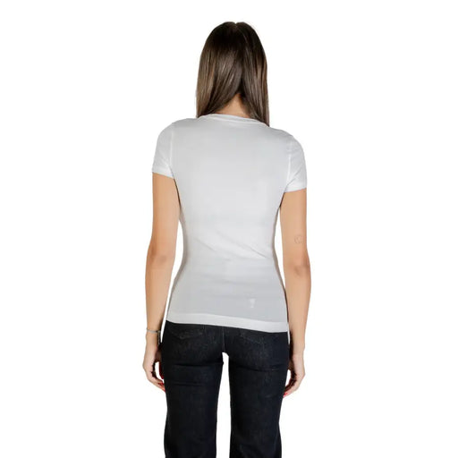 Woman wearing Guess White Rhinestone Round Neck Tee and dark jeans, back view