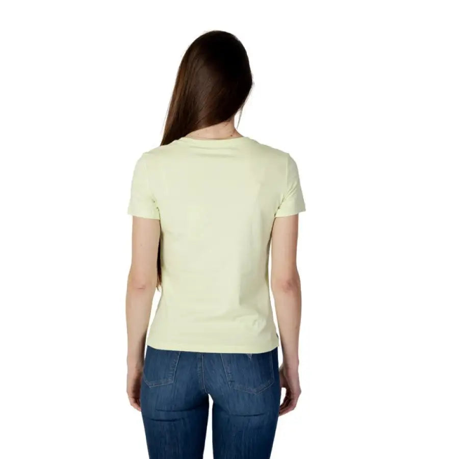 Woman in yellow shirt and jeans showcasing urban city style for Guess Women T-Shirt