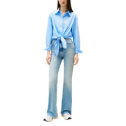 Woman wearing Tommy Hilfiger light blue organic cotton button shirt with flared jeans and sneakers