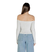 Woman wearing a white off-the-shoulder long-sleeved top with wide-leg jeans