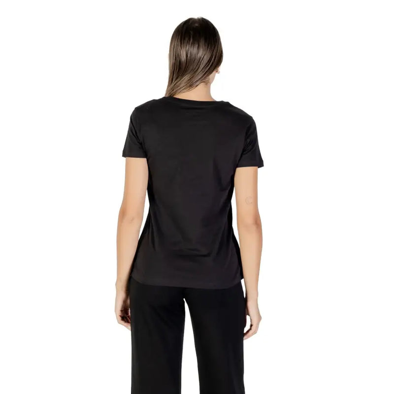 Woman wearing Armani Exchange short black round neck cotton T shirt and black pants from behind