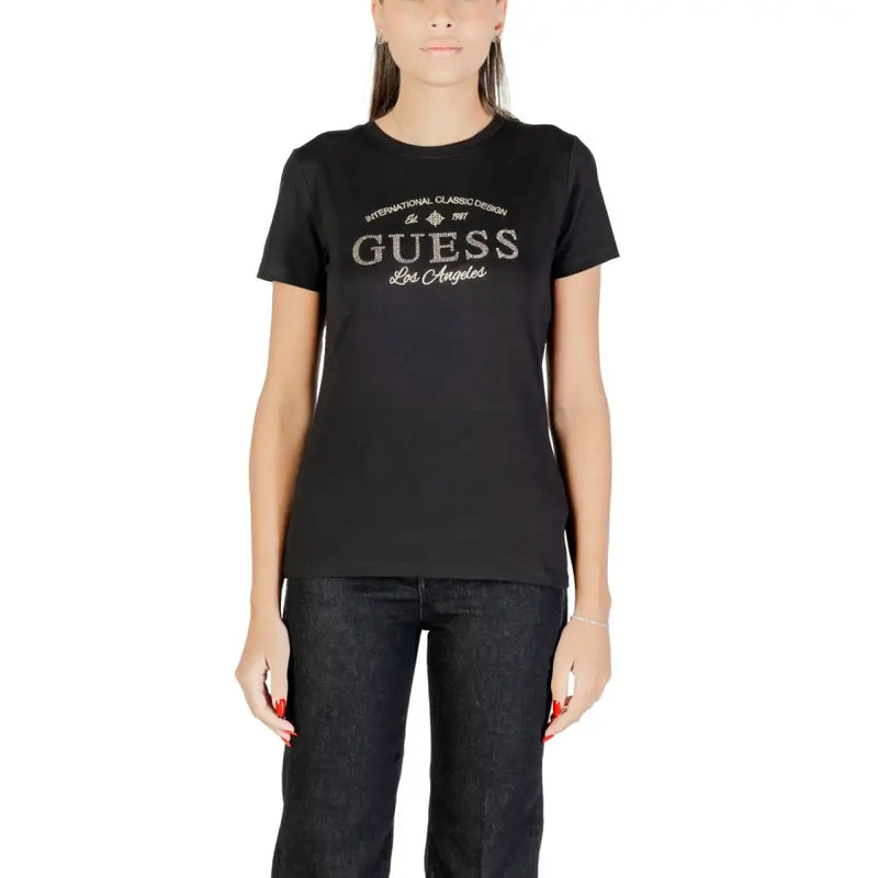 Woman wearing short-sleeved black Guess T-shirt with silver GUESS Los Angeles graphic