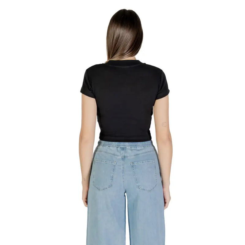 Woman wearing Calvin Klein Jeans black printed short sleeve crop top with light blue wide-leg jeans