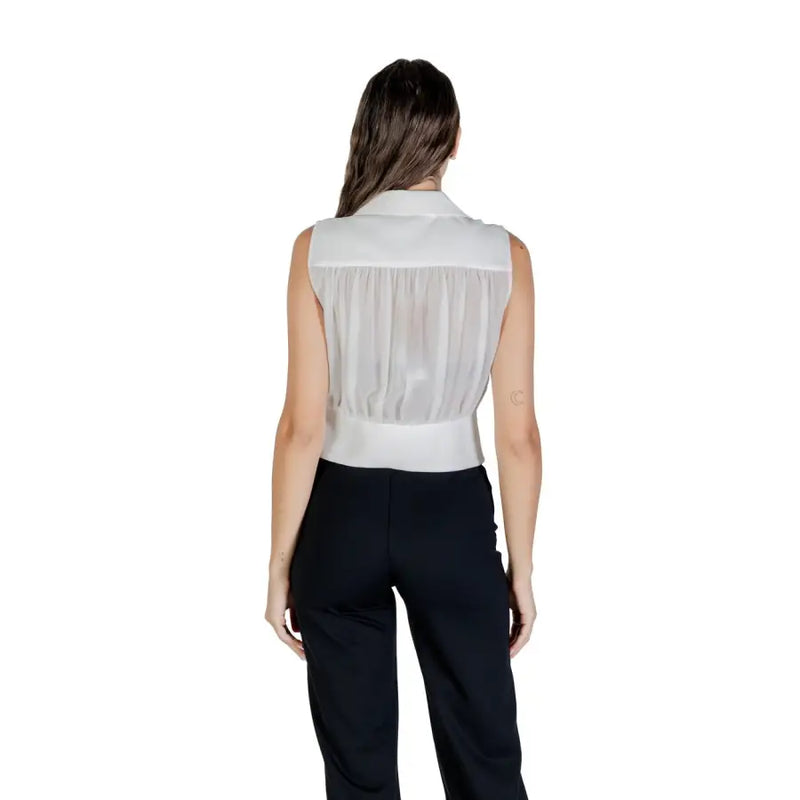 Woman wearing a white sleeveless sheer V-neck zip top with black pants for Fall Winter fashion