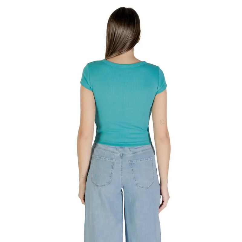 Woman wearing teal short-sleeve Calvin Klein Jeans T-shirt with light blue wide-leg jeans