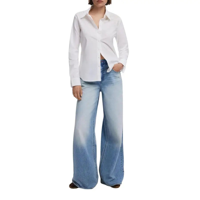 Woman wearing Desigual white long sleeve shirt with light wash wide-leg jeans for fall winter